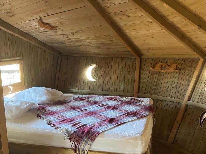 Cabane en bois avec lit confortable et décoration chaleureuse en bois.