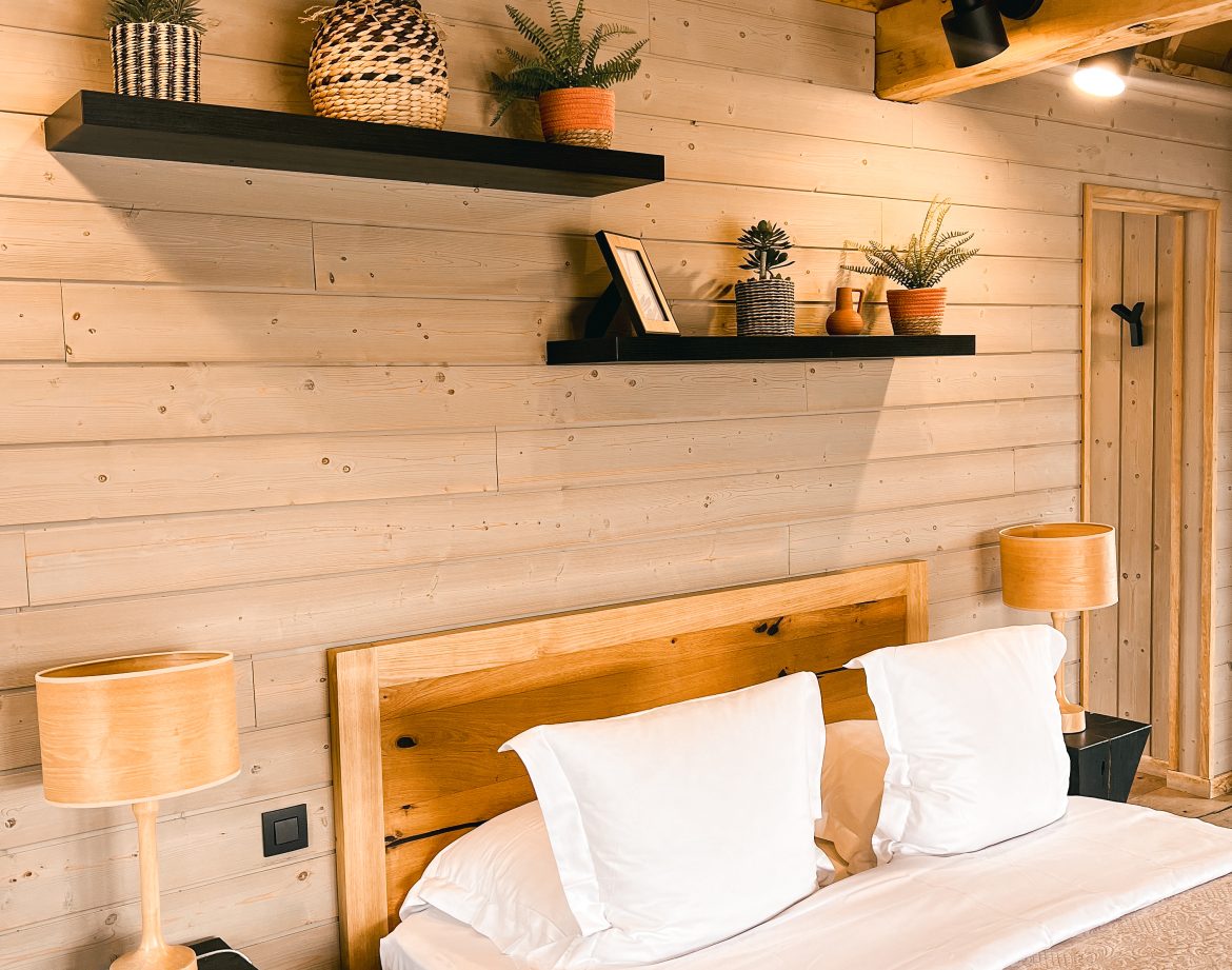 Chalet en bois chaleureux avec lit douillet et décoration végétale moderne.