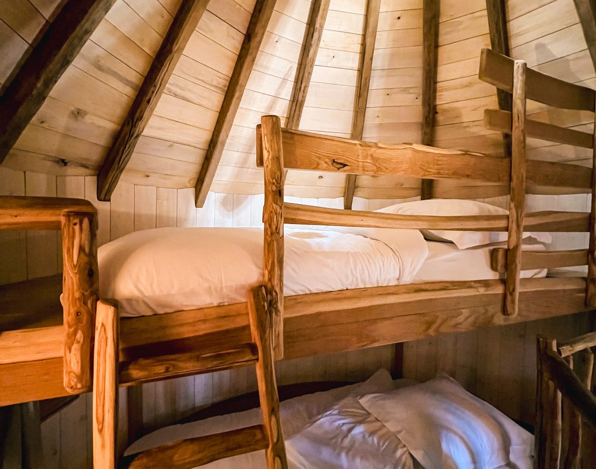 Cabane en bois avec lits superposés, ambiance chaleureuse et naturelle.