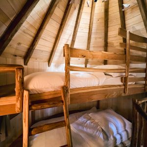 Cabane en bois avec lits superposés, ambiance chaleureuse et naturelle.