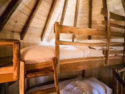 Cabane en bois avec lits superposés, ambiance chaleureuse et naturelle.