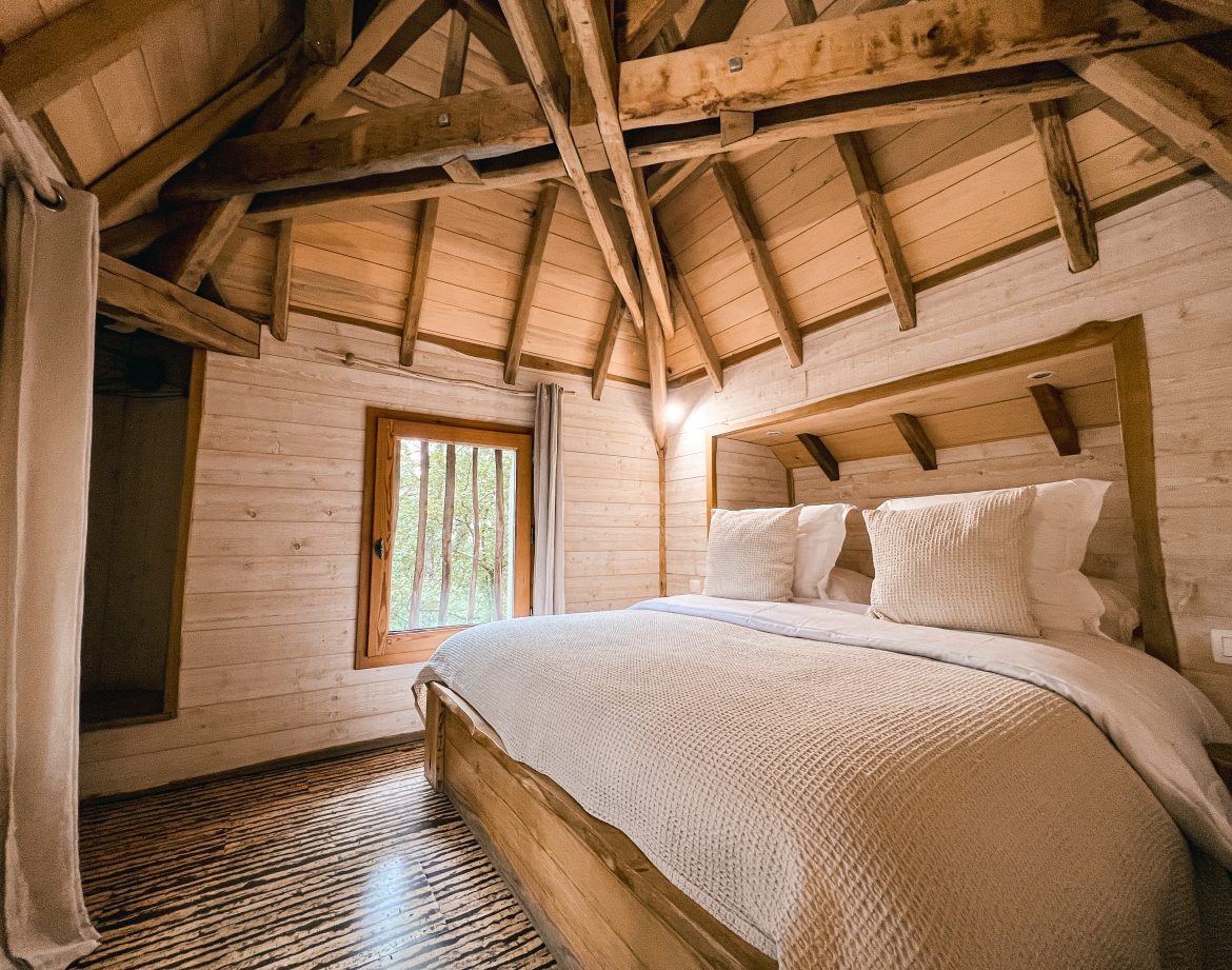 Cabane en bois avec un lit douillet et un plafond en bois chaleureux.