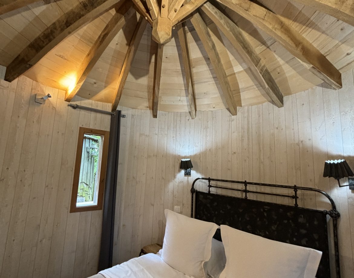 Chalet en bois avec un plafond en bois en étoile et un lit douillet.