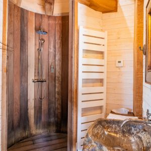 Douche en bois dans un hébergement insolite en Aquitaine, ambiance chaleureuse et naturelle.
