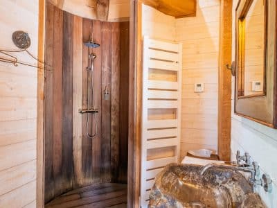 Douche en bois dans un hébergement insolite en Aquitaine, ambiance chaleureuse et naturelle.