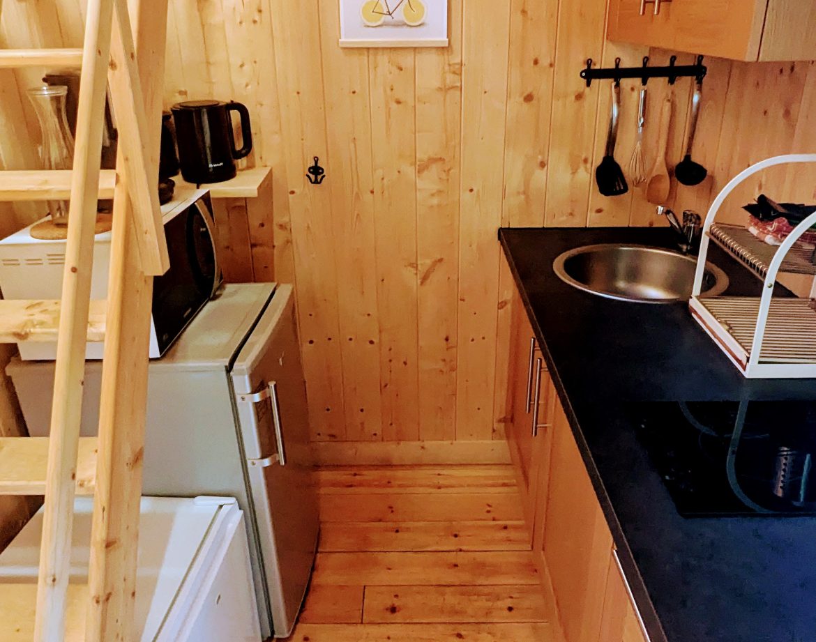 Cottage en bois chaleureux avec cuisine équipée et escaliers en bois.