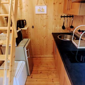 Cottage en bois chaleureux avec cuisine équipée et escaliers en bois.
