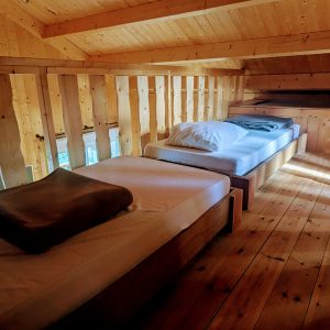 Chalet en bois avec lits simples, ambiance chaleureuse et lumineuse en Auvergne-Rhône-Alpes.