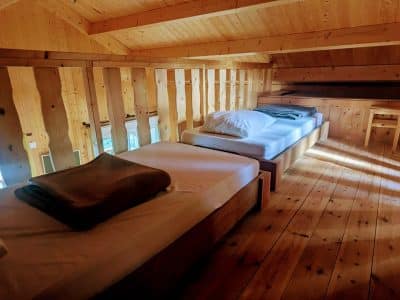 Chalet en bois avec lits simples, ambiance chaleureuse et lumineuse en Auvergne-Rhône-Alpes.
