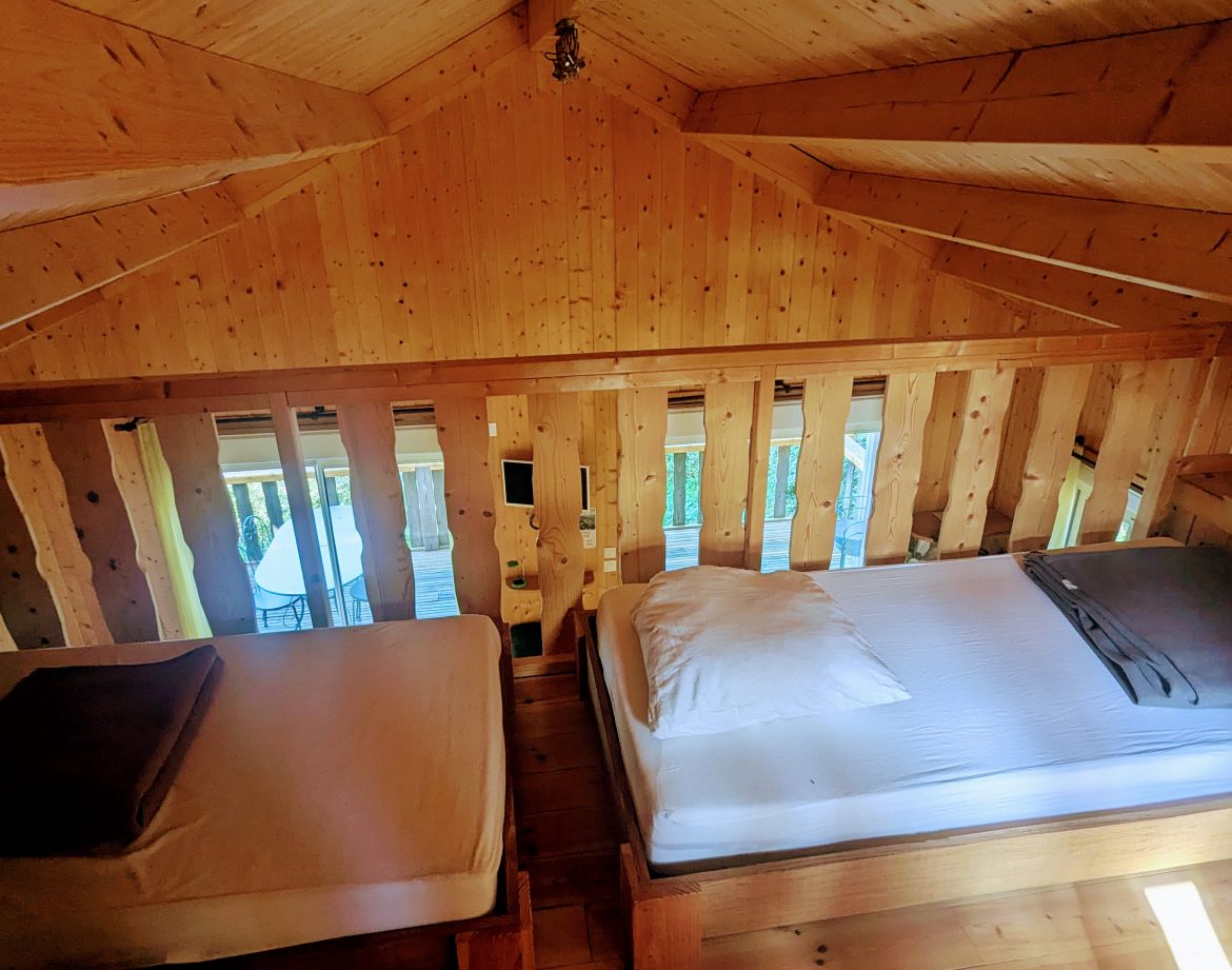 Cabane en bois avec lits douillets et vue sur la nature environnante.
