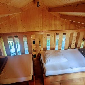 Cabane en bois avec lits douillets et vue sur la nature environnante.