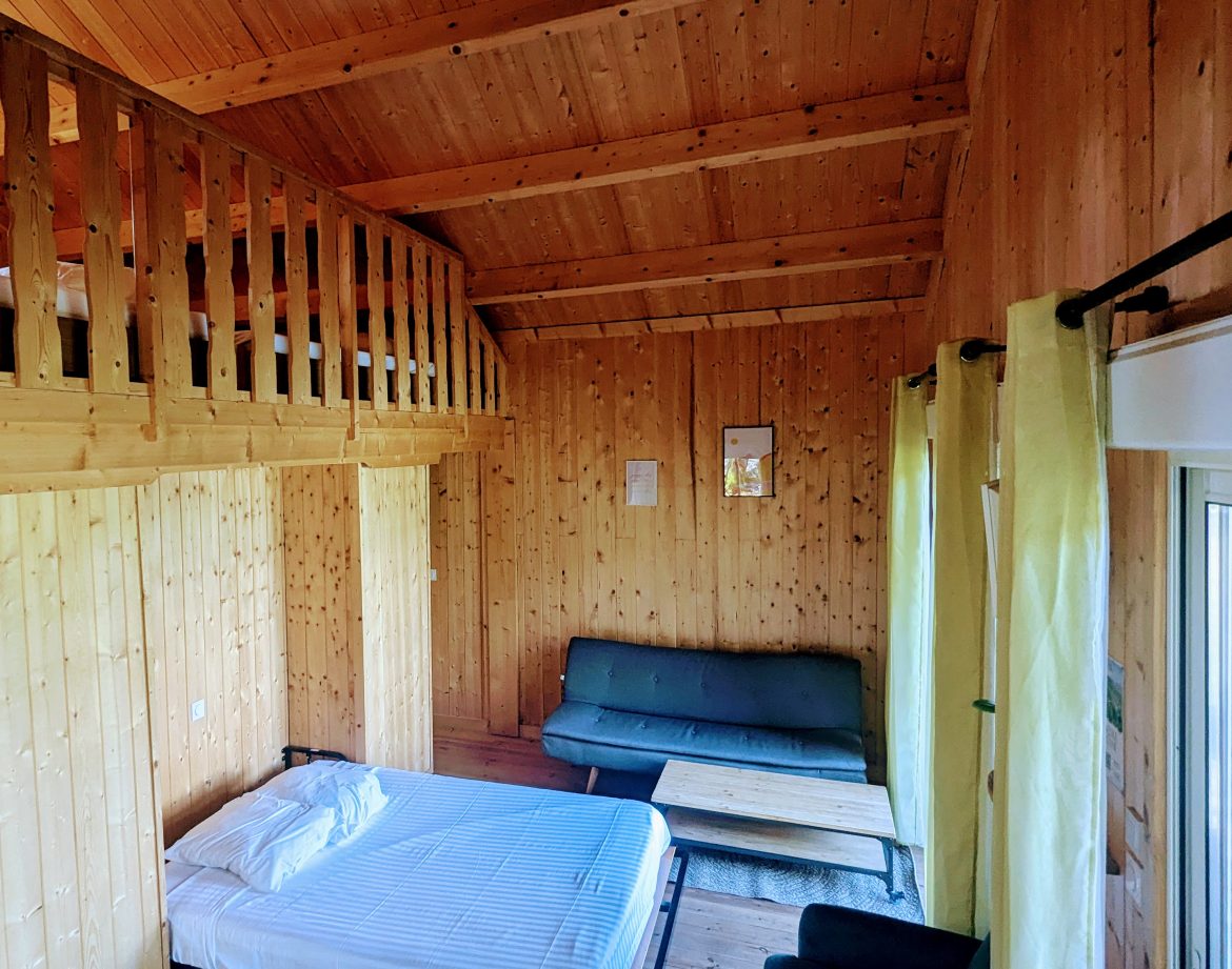 Cabane en bois avec mezzanine, intérieur chaleureux et lumineux en Auvergne-Rhône-Alpes.