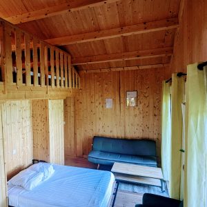 Cabane en bois avec mezzanine, intérieur chaleureux et lumineux en Auvergne-Rhône-Alpes.