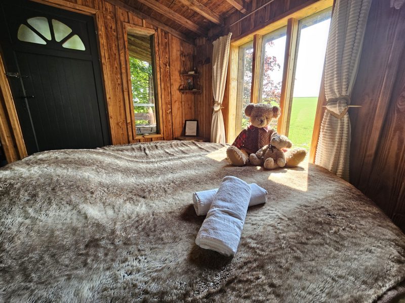 Cabane en bois chaleureuse avec un ours en peluche sur un lit moelleux.