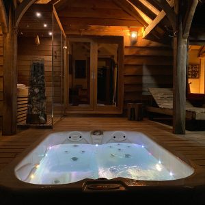 Hébergement insolite en Aquitaine : chalet en bois avec jacuzzi lumineux en extérieur.