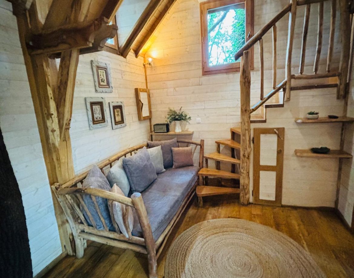 Cabane en bois en Aquitaine, avec un coin salon cosy et un escalier en colimaçon.