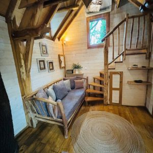 Cabane en bois en Aquitaine, avec un coin salon cosy et un escalier en colimaçon.