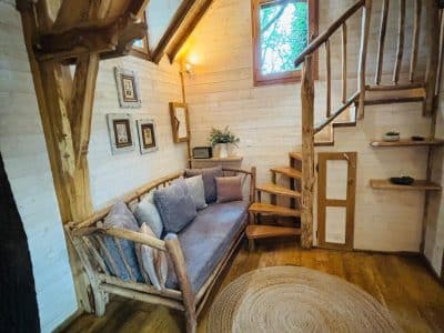 Cabane en bois en Aquitaine, avec un coin salon cosy et un escalier en colimaçon.
