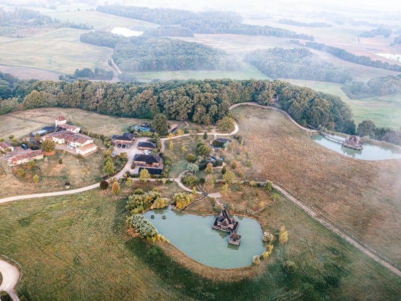 Domaine rural avec gîtes, entouré de verdure et de lacs paisibles.