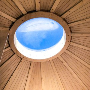Hébergement insolite en Aquitaine : intérieur en bois avec un puits de lumière circulaire.