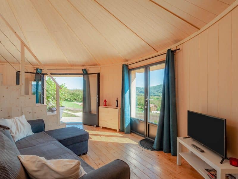 Cabane moderne avec vue panoramique, intérieur en bois chaleureux et lumineux.
