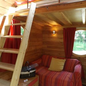 Cabane en bois avec mezzanine, décor chaleureux et vue sur la nature.