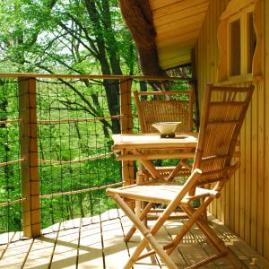 Cabane perchée en Nouvelle-Aquitaine avec balcon en bois et vue sur la nature verdoyante.