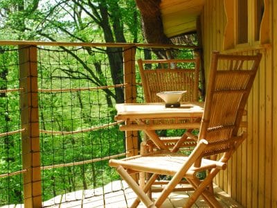 Cabane perchée en Nouvelle-Aquitaine avec balcon en bois et vue sur la nature verdoyante.