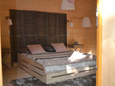 Chalet en bois à Nouvelle-Aquitaine, intérieur cosy avec lit en palette et tapis moelleux.