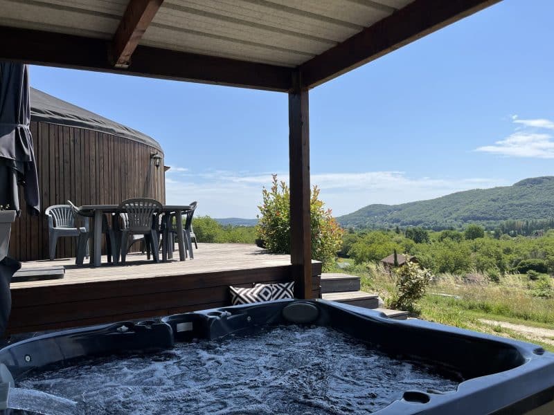 Yourte avec jacuzzi, vue panoramique sur la nature environnante et terrasse en bois.