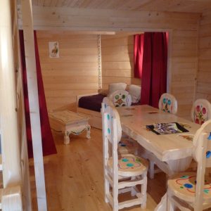 Cabane en bois colorée avec un intérieur chaleureux et une table conviviale.