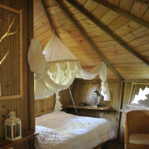 Cabane en bois avec lit douillet et décoration naturelle, ambiance chaleureuse.