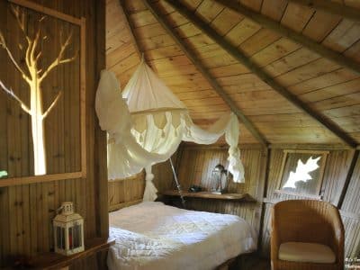 Cabane en bois avec lit douillet et décoration naturelle, ambiance chaleureuse.