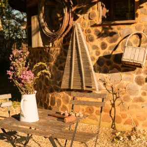 Hébergement insolite en Aquitaine : cabane en pierre avec une terrasse en bois et des fleurs.