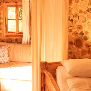 Hébergement insolite en Aquitaine : cabane en bois avec murs en rondins et lit douillet.