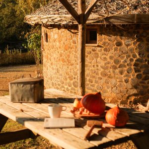 Hébergement insolite en Aquitaine : cabane en pierre avec table en bois et décor automnal.