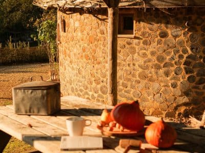 Hébergement insolite en Aquitaine : cabane en pierre avec table en bois et décor automnal.