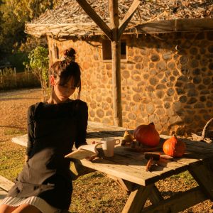 Hébergement insolite en Aquitaine : cabane en pierre avec une femme lisant à table.