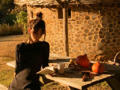 Hébergement insolite en Aquitaine : cabane en pierre avec une femme lisant à table.