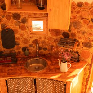 Hébergement insolite en Aquitaine : kitchenette en bois avec mur en rondins chaleureux.