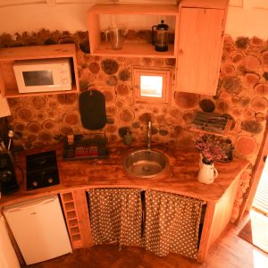 Hébergement insolite en Aquitaine : cuisine en bois avec murs en rondins et lumière naturelle.