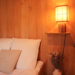 Chalet en bois chaleureux avec lampadaire et vase de fleurs séchées.