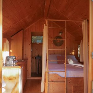 Cabane en bois chaleureuse avec lit douillet et cuisine intégrée.