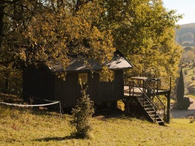 Cabane en bois perchée, entourée darbres dorés en Aquitaine. Idéal pour un séjour nature.