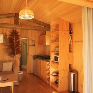 Cabane en bois chaleureuse avec cuisine équipée et décoration naturelle.