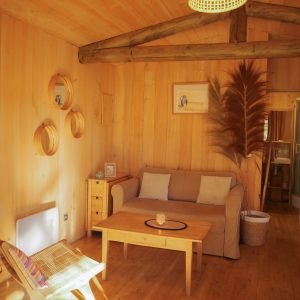 Hébergement insolite en Aquitaine : chalet en bois avec salon lumineux et décor chaleureux.