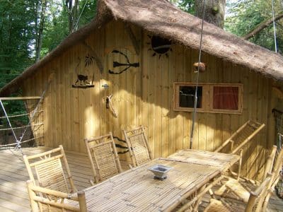 Cabane dans les arbres en Nouvelle-Aquitaine, avec terrasse en bois et décorations naturelles.