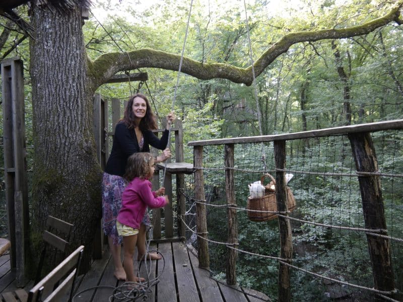 Cabane dans les arbres, avec une vue sur la forêt verdoyante et une famille heureuse.