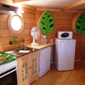 Hébergement insolite en bois en Nouvelle-Aquitaine, avec cuisine colorée et décor végétal.
