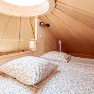 Cabane en bois avec un plafond en bois clair et un puits de lumière accueillant.